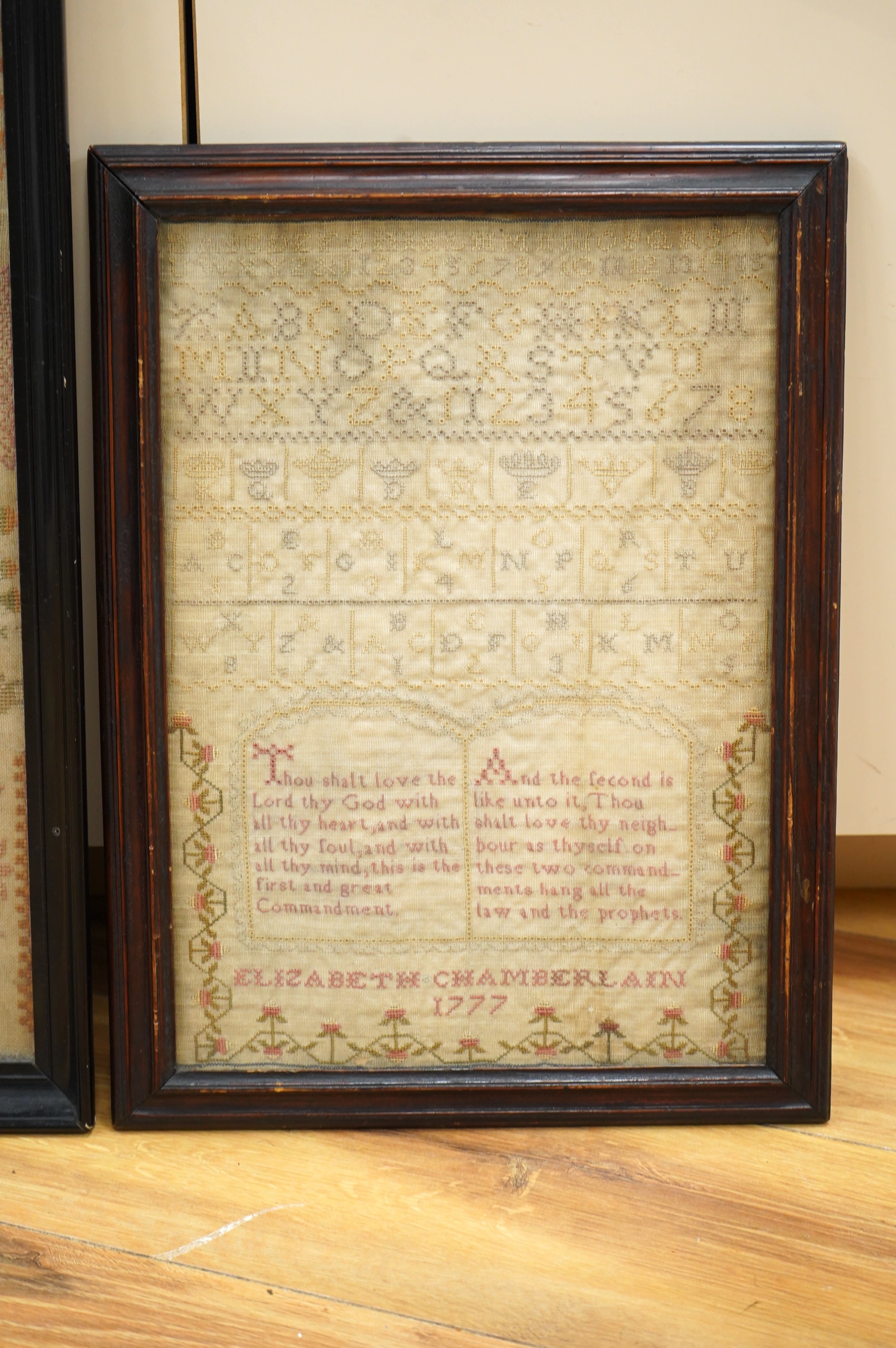 Two samplers; one late 18th century, the other early 20th century, the 18th century sampler by Elizabeth Chamberlain dated 1777, worked with an alphabet and framed verse bordered with vineous flowers, the later sampler b